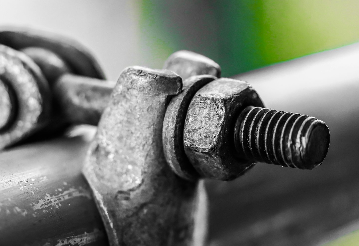 A weathered metal industrial clamp secured onto a dark pipe.
