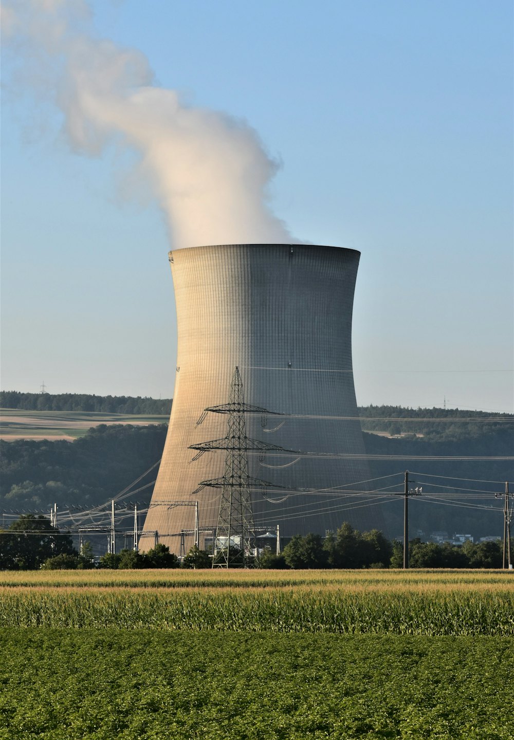 Industrial cooling tower releases steam against a blue sky.